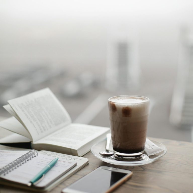 Notizbuch, Smartphonr, Buch und Latte Macchiato. Blick aus dem Fenster.